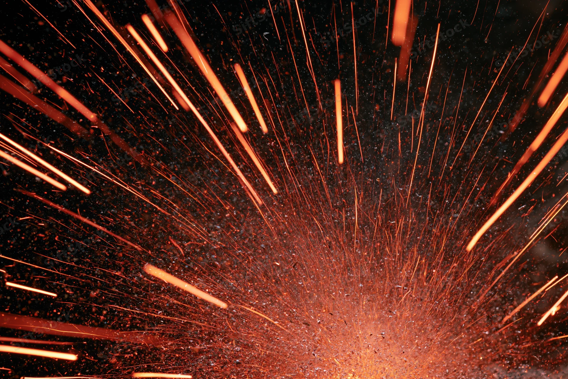 Burst of glowing orange sparks radiating outward from a central point against a dark background