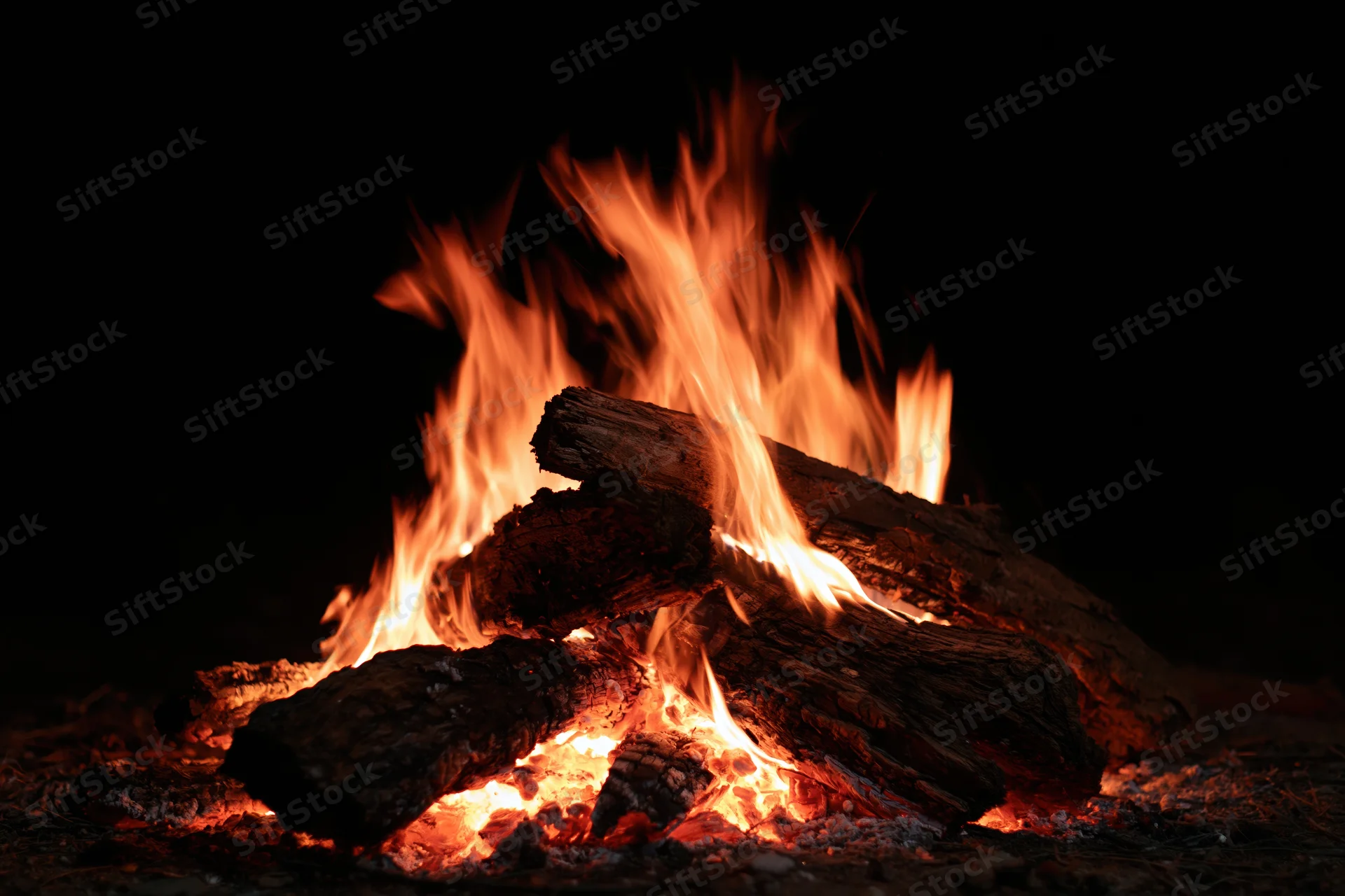 Campfire burning with stacked logs at night outdoors
