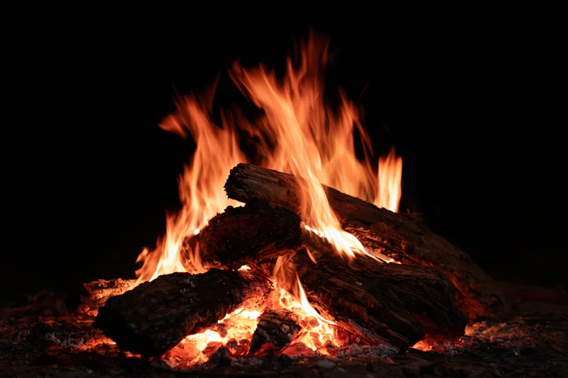 Campfire burning with stacked logs at night outdoors