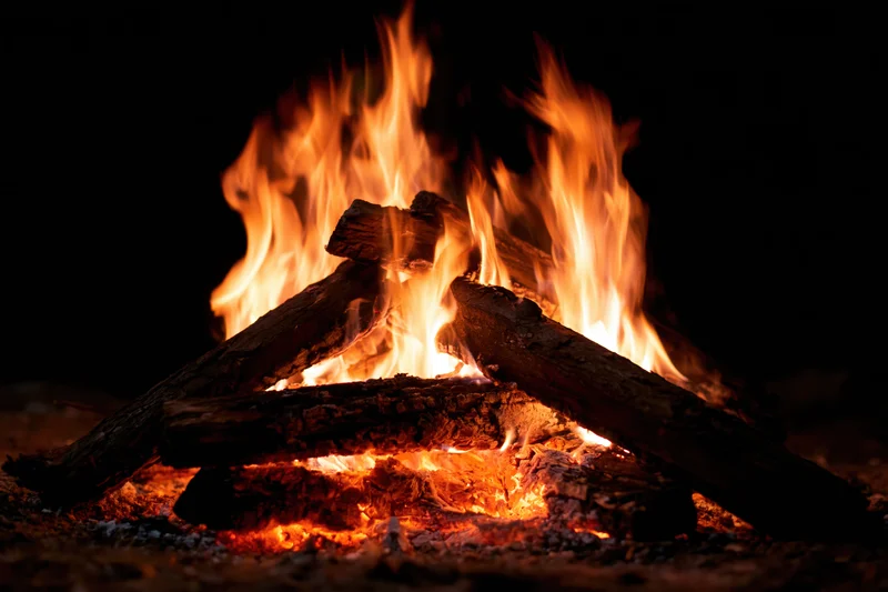 Campfire burning with stacked logs at night outdoors