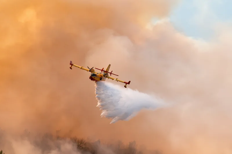Canadair cl415 aircraft releasing water over smoky forest landscape