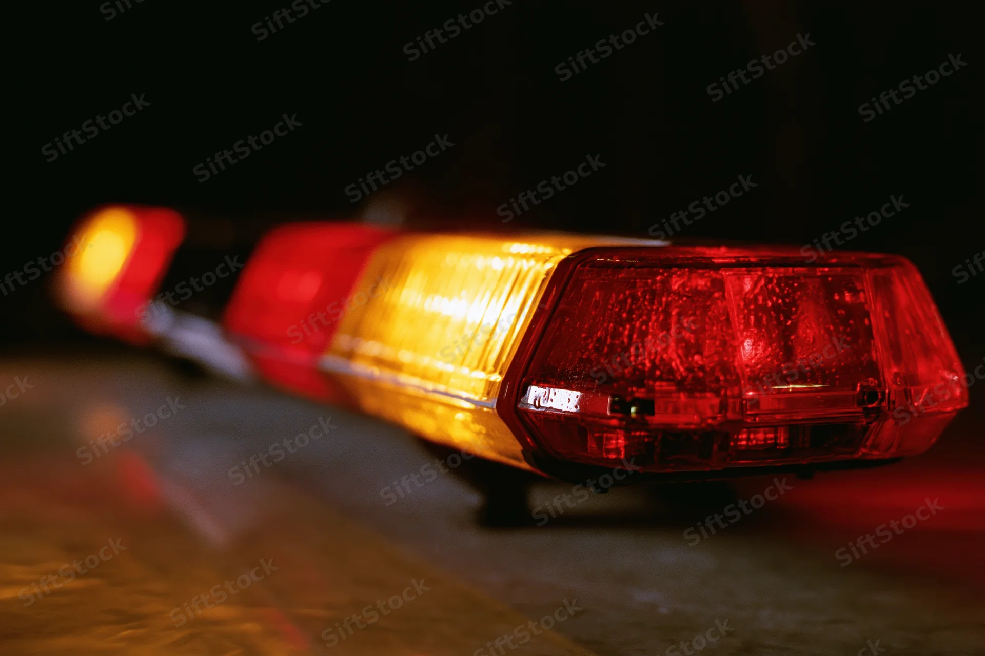 Close-up of a red and amber emergency light bar mounted on a vehicle at night