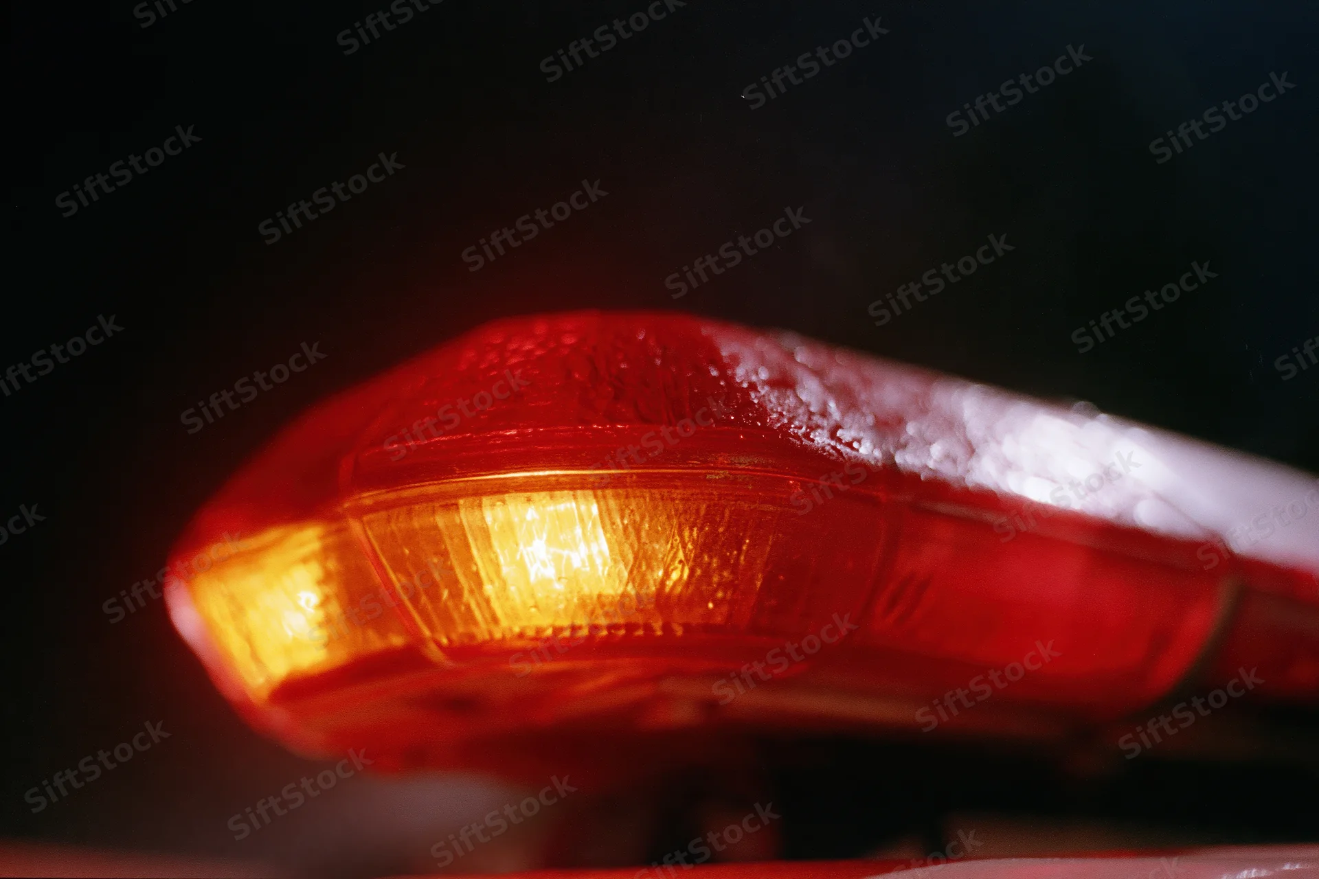 Close-up of a red emergency vehicle light bar glowing in the dark