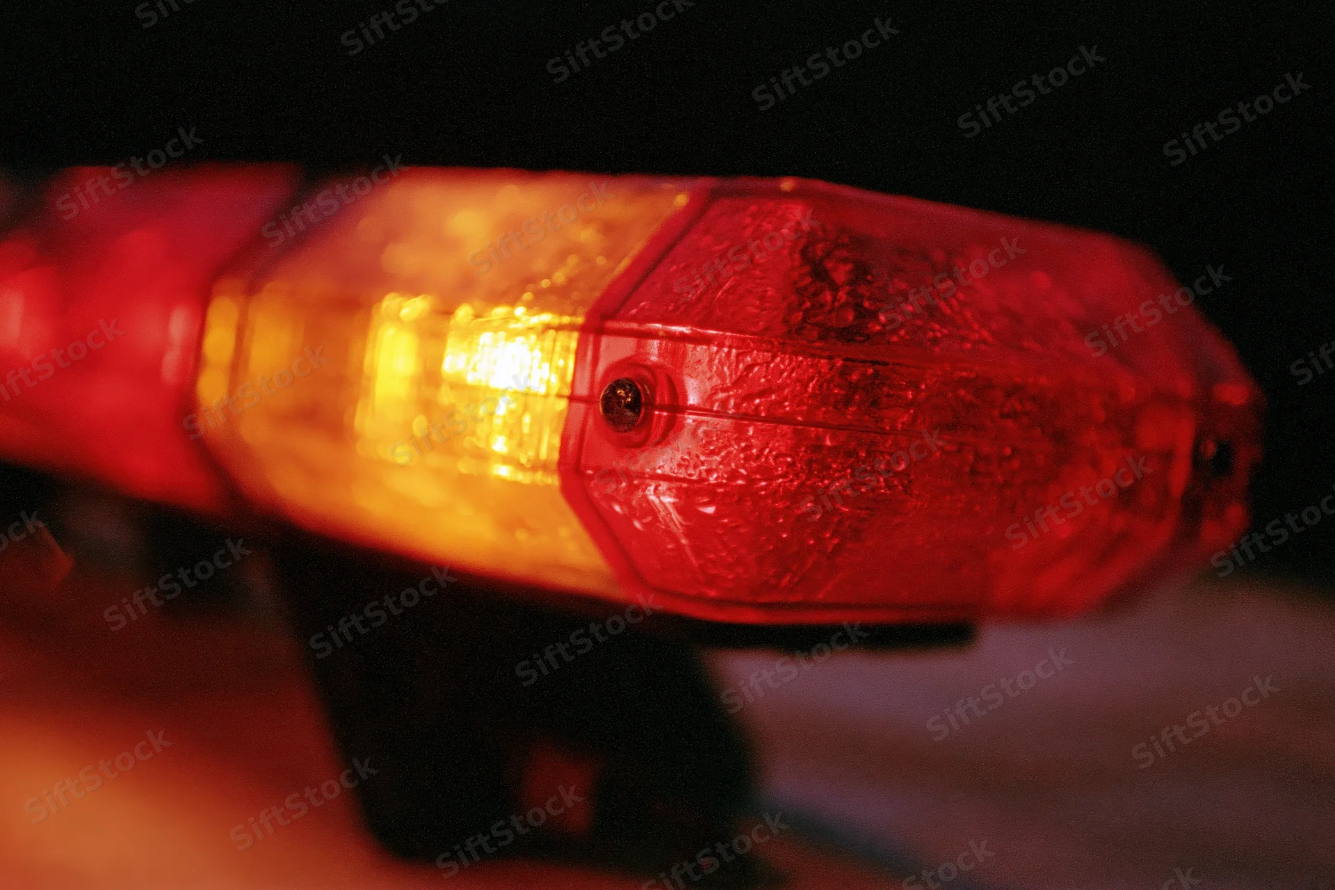 Close-up of red and amber emergency vehicle light bar flashing at night