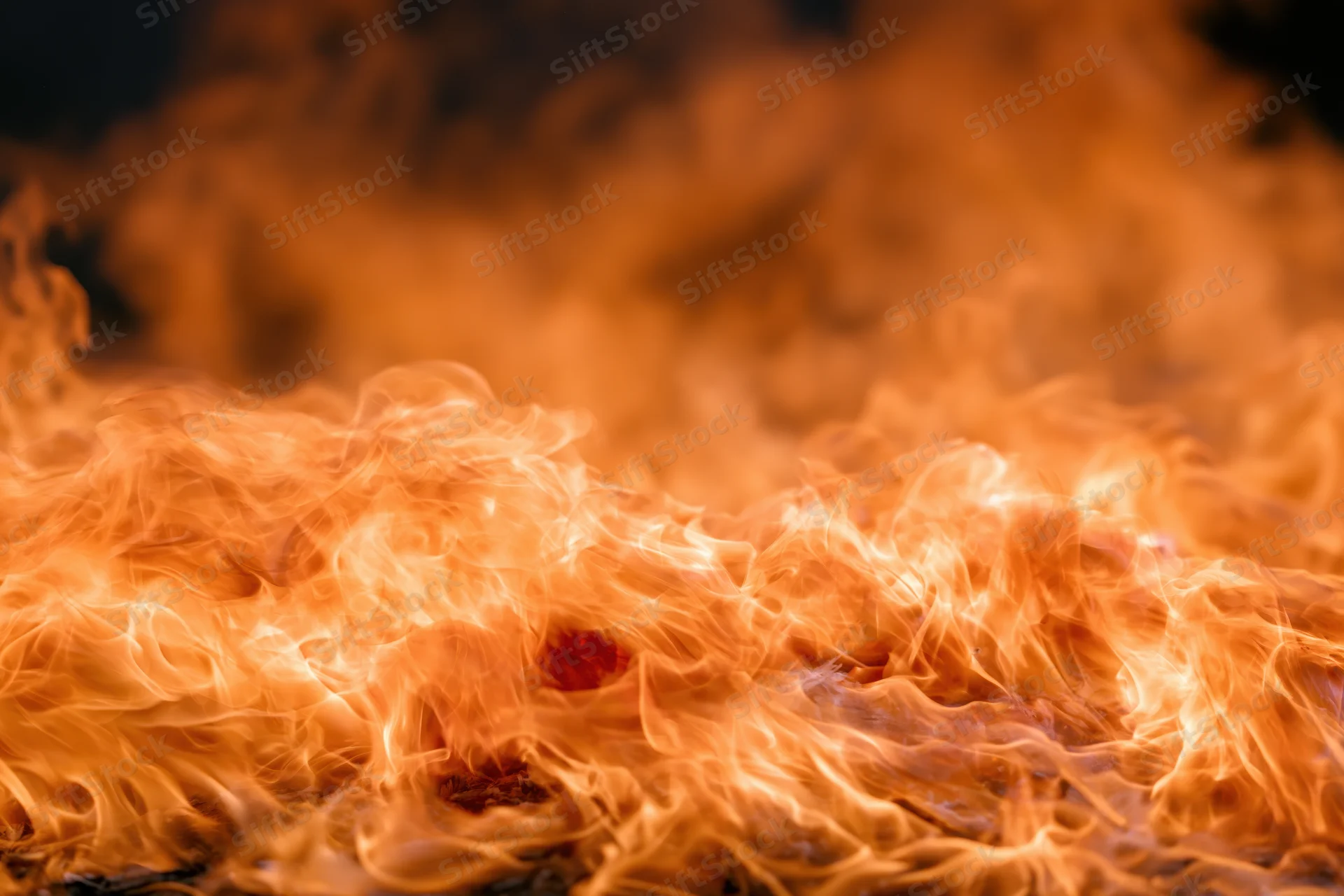 Intense flames burning across the frame with swirling orange and red tongues of fire
