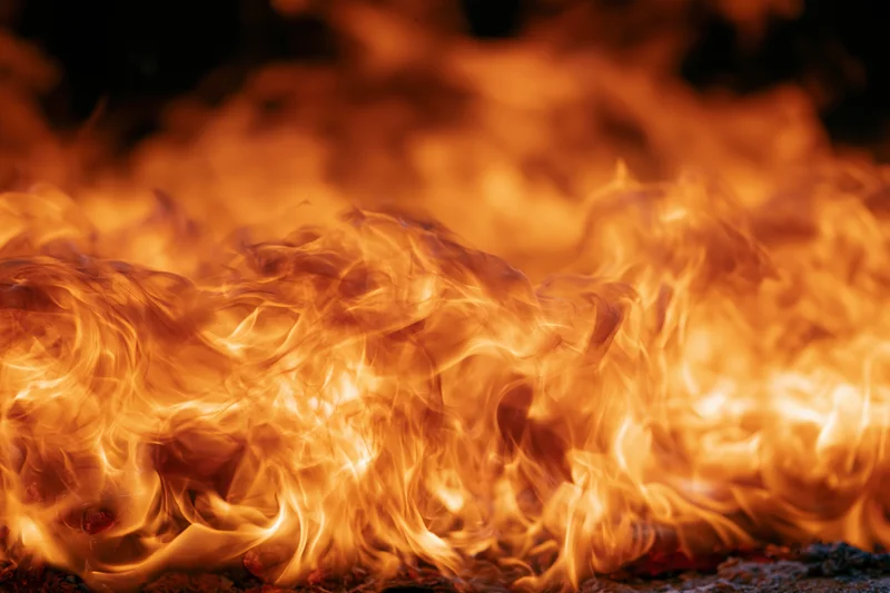 Intense flames burning across the frame with swirling orange and yellow tongues of fire
