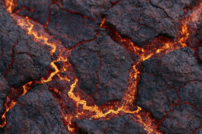 Close-up of cooling volcanic lava crust with glowing cracks and dark surface