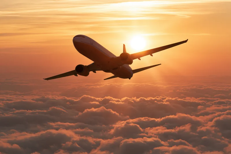 Commercial passenger jet flying above cloud layer at sunset