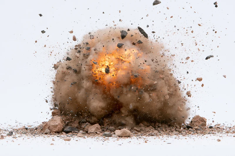 Explosion mid-burst with flying debris and smoke against white background