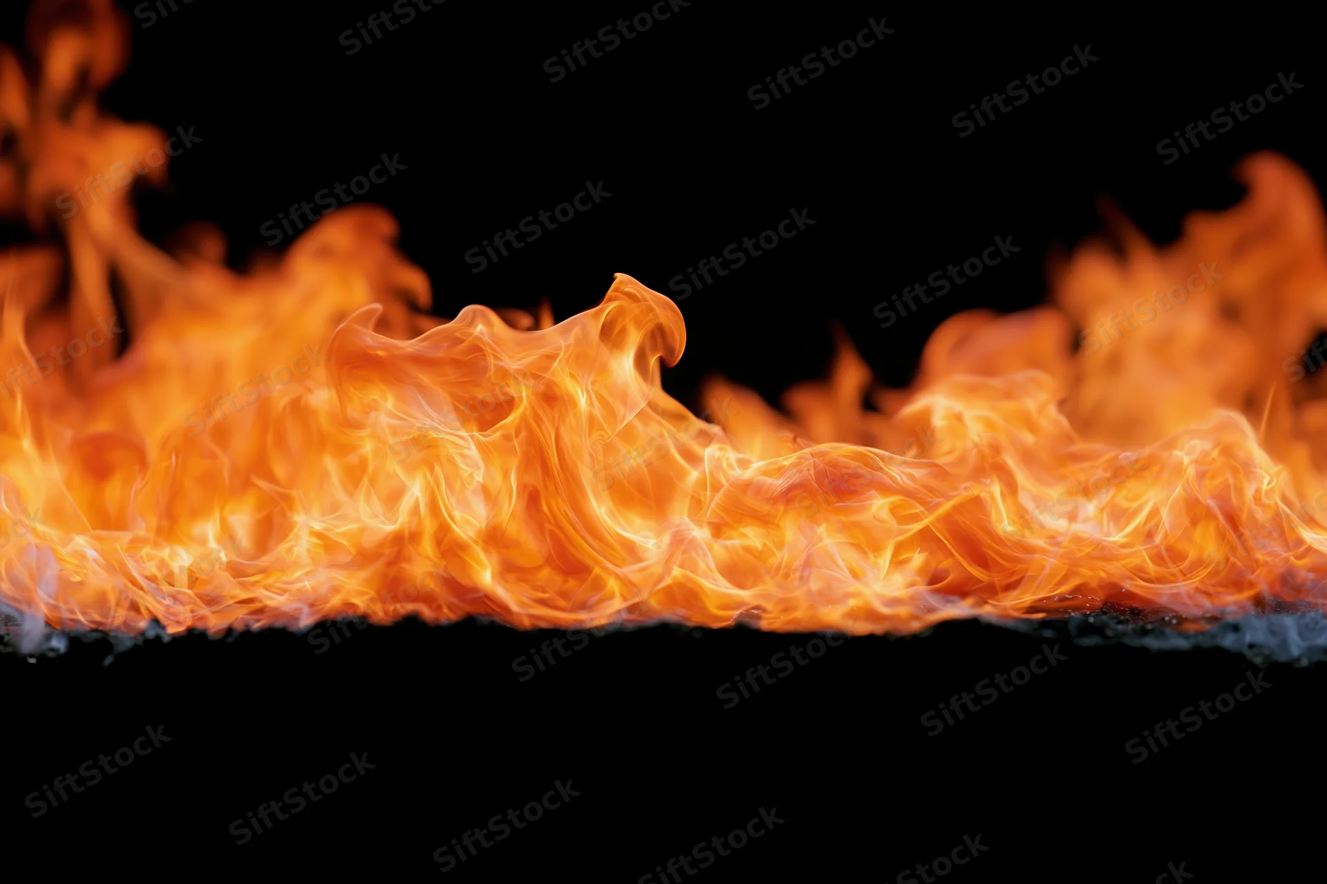 Dynamic fire flames spreading horizontally across frame isolated on black background
