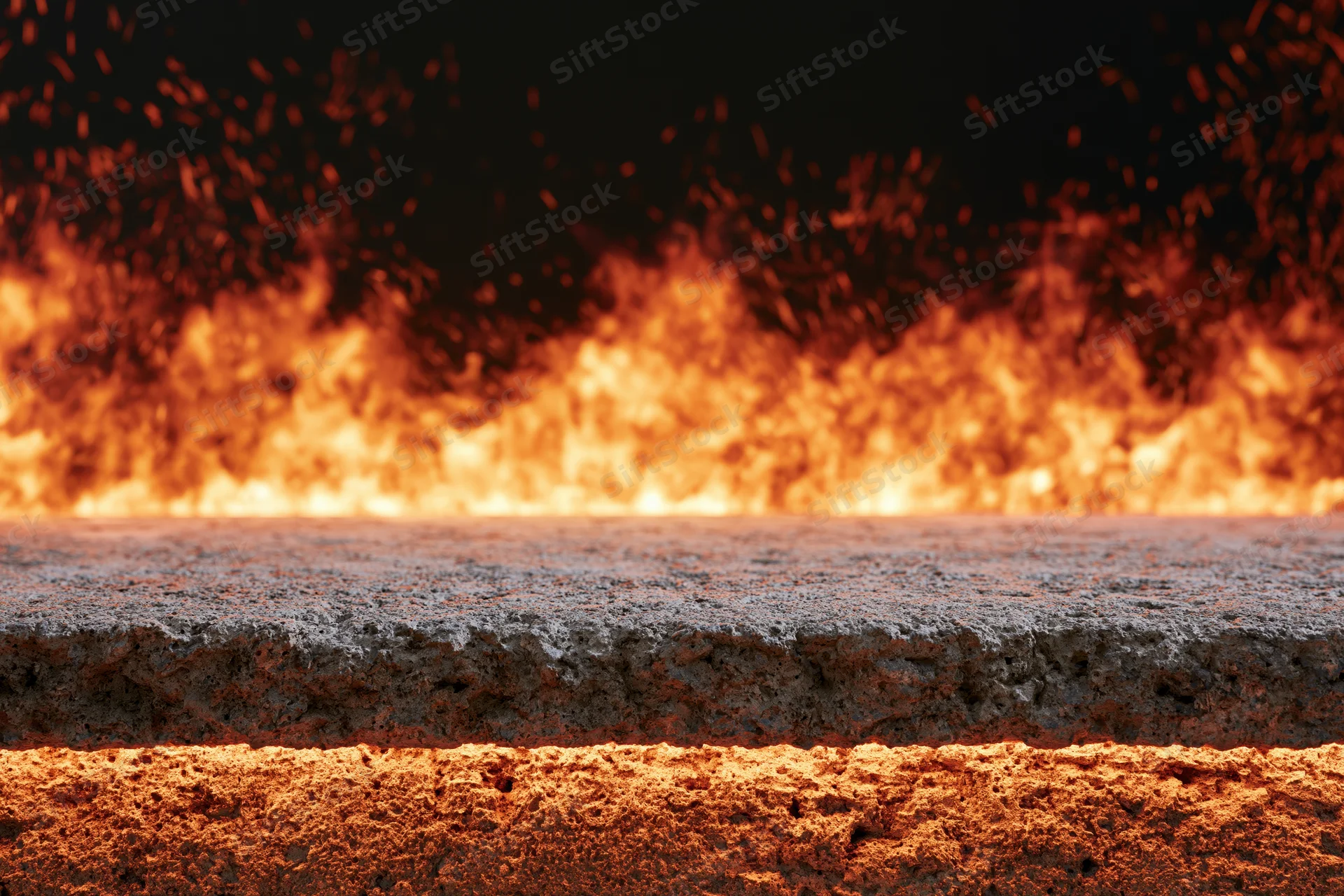 Concrete ledge in foreground with flames and sparks behind at night