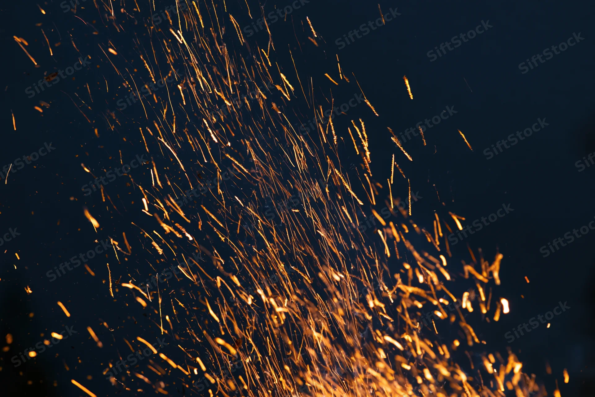 Glowing sparks flying upward against a dark night sky