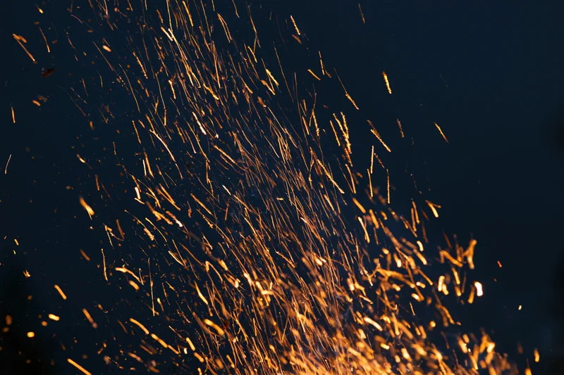 Glowing sparks flying upward against a dark night sky