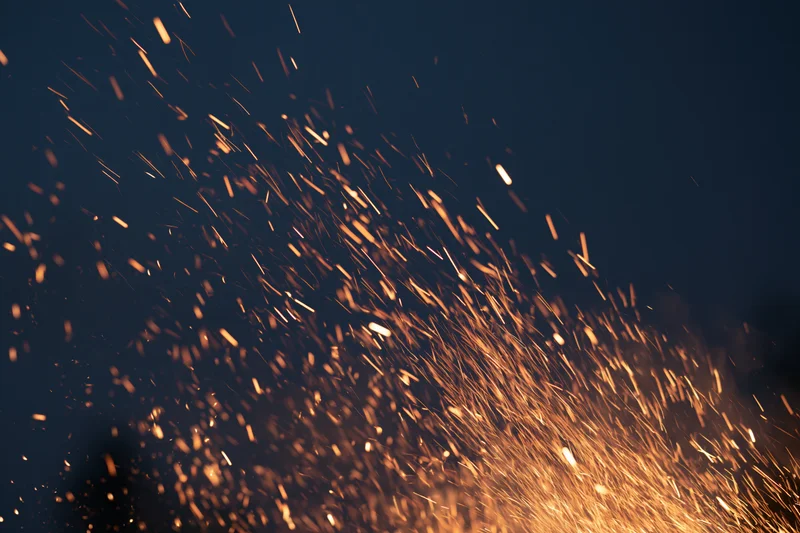 Glowing sparks flying upward against a dark night sky