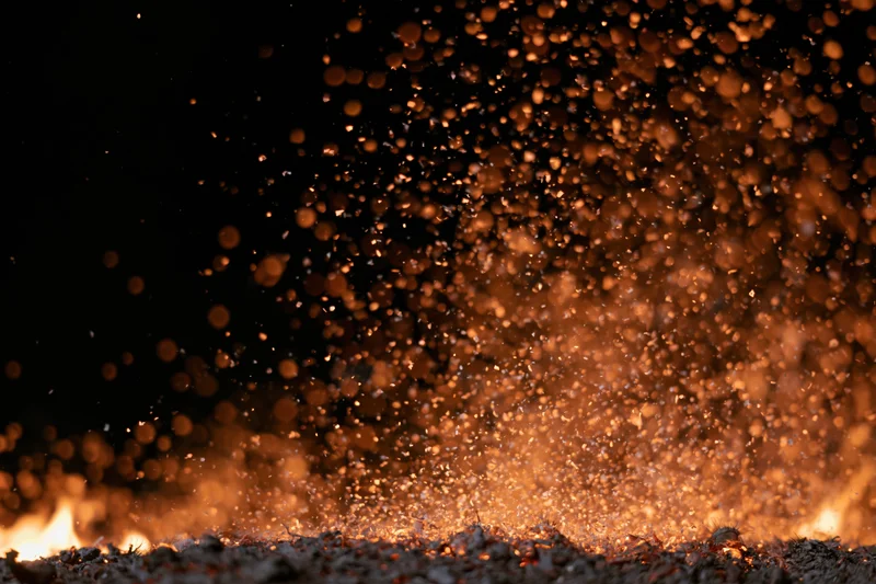 Fire embers and sparks rising from flames at night