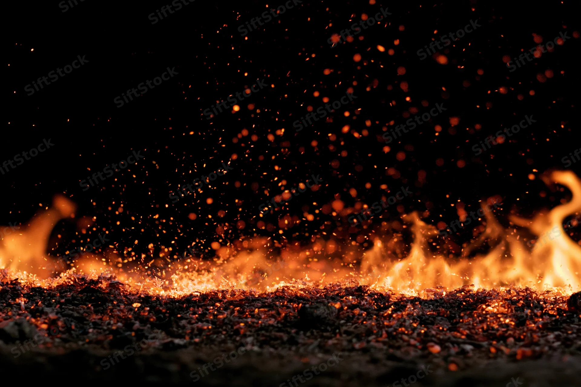 Flames and glowing embers burning along the bottom edge against a dark background