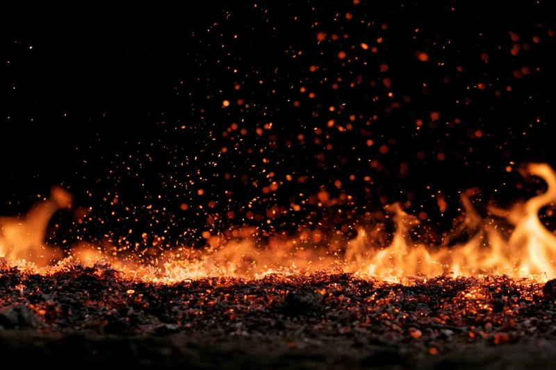 Flames and glowing embers burning along the bottom edge against a dark background