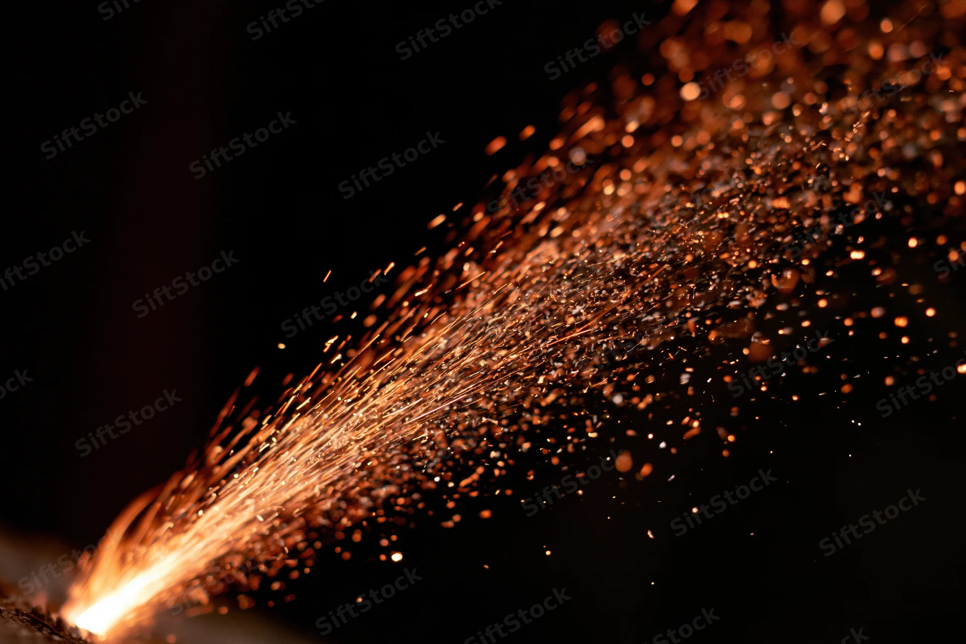 Sparks bursting upward in a fiery stream against a dark background