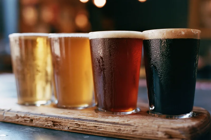 Four craft beer tasting glasses in a row on a wooden tray