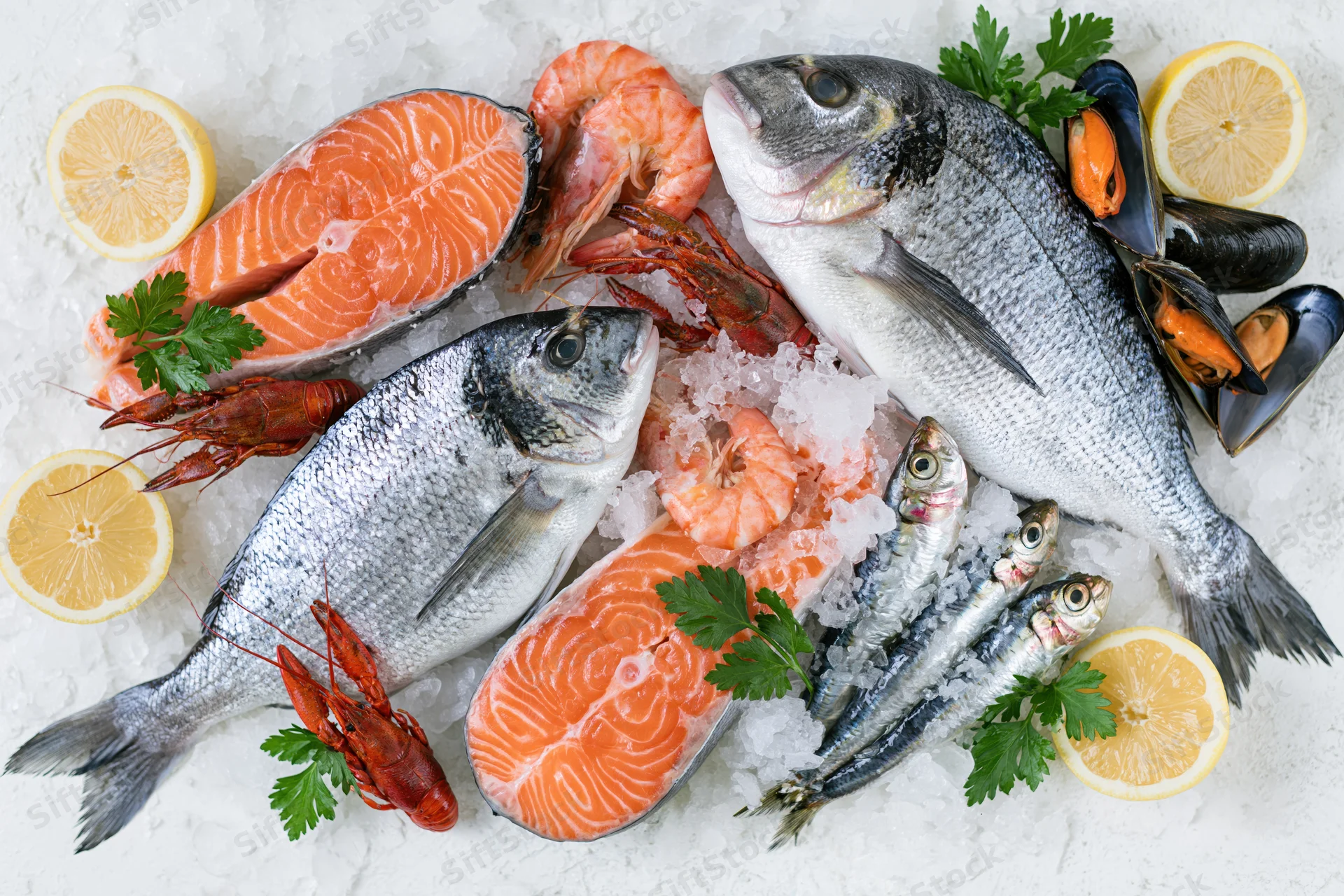 Fresh whole sea bream salmon steaks prawns crawfish mussels arranged on ice with lemon and parsley