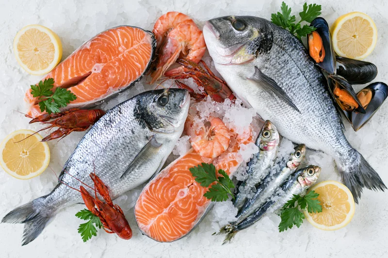 Fresh whole sea bream salmon steaks prawns crawfish mussels arranged on ice with lemon and parsley