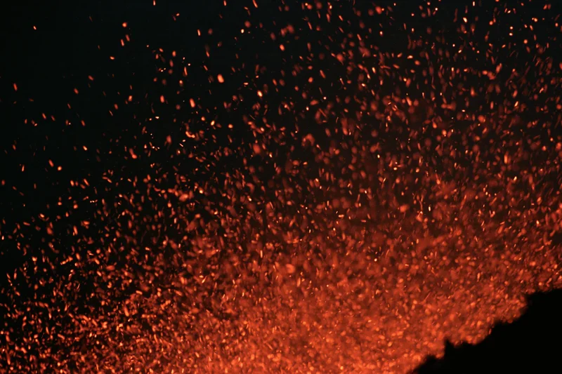 Glowing orange and red sparks rising upward against a dark background