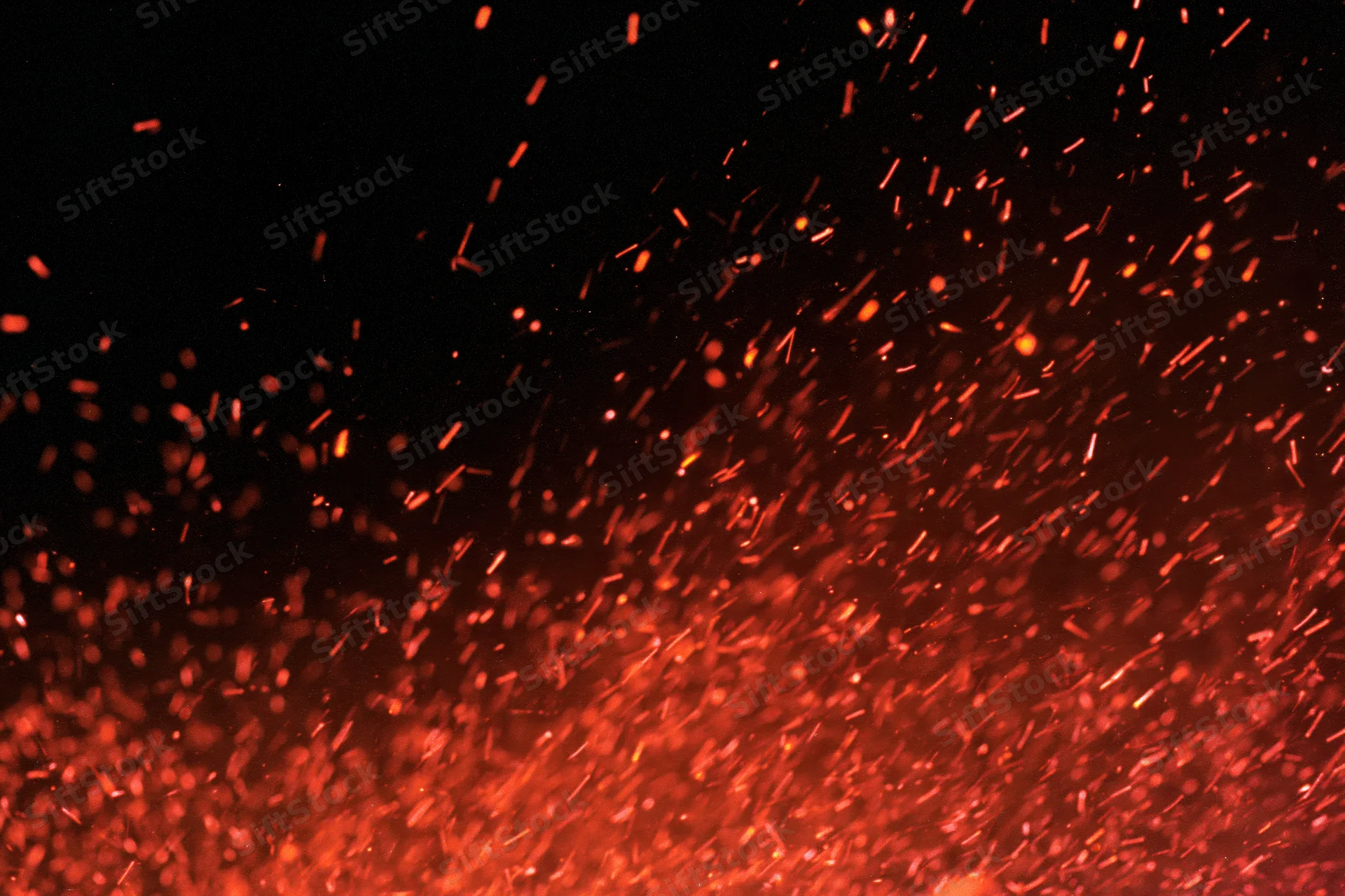Glowing orange and red sparks flying upward against a dark background