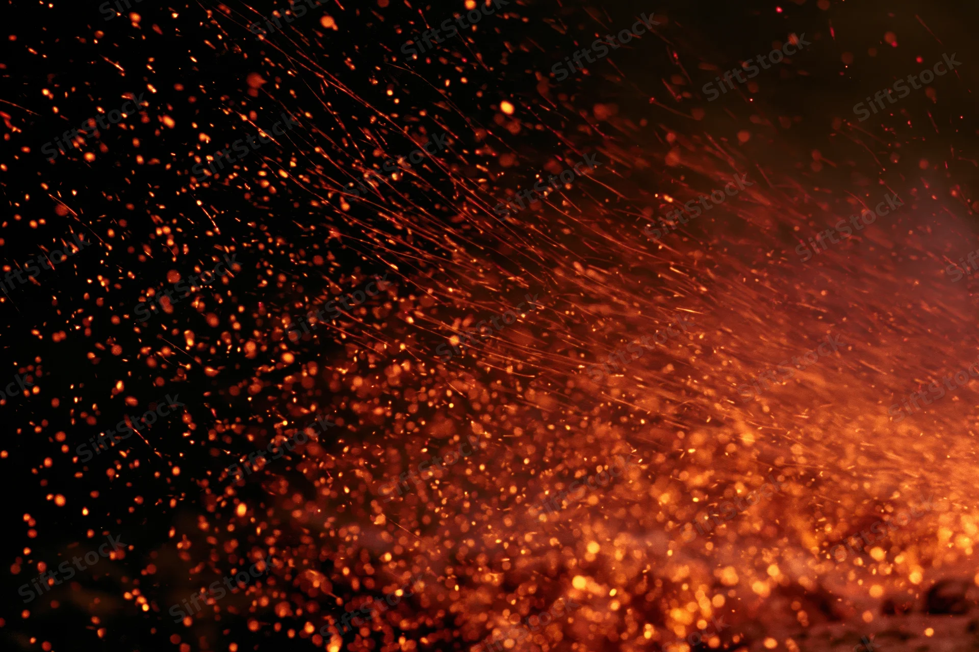 Glowing orange and red sparks flying upward against dark background