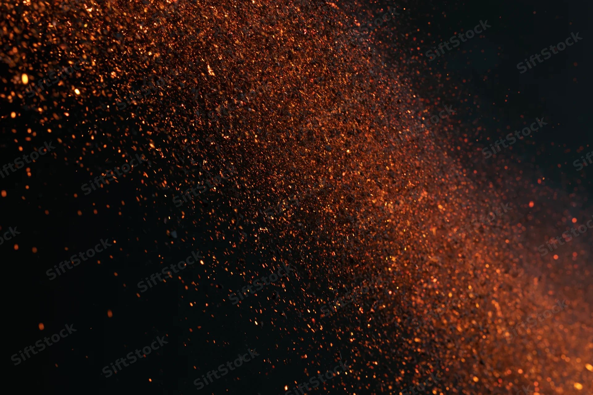 Glowing orange sparks flying through dark space in dynamic burst
