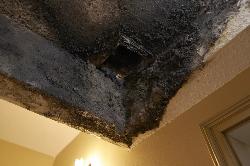 Fire-damaged ceiling with soot and charred texture in a room corner