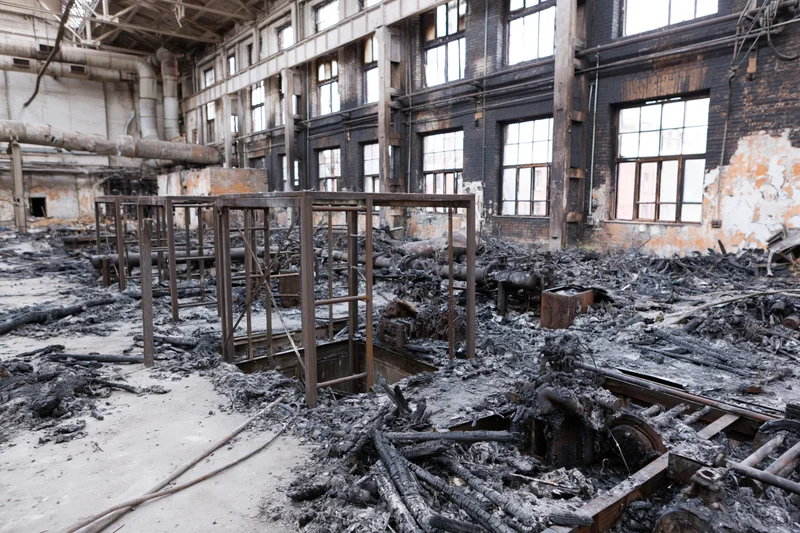 Interior of a fire-damaged industrial factory with charred debris and exposed framework