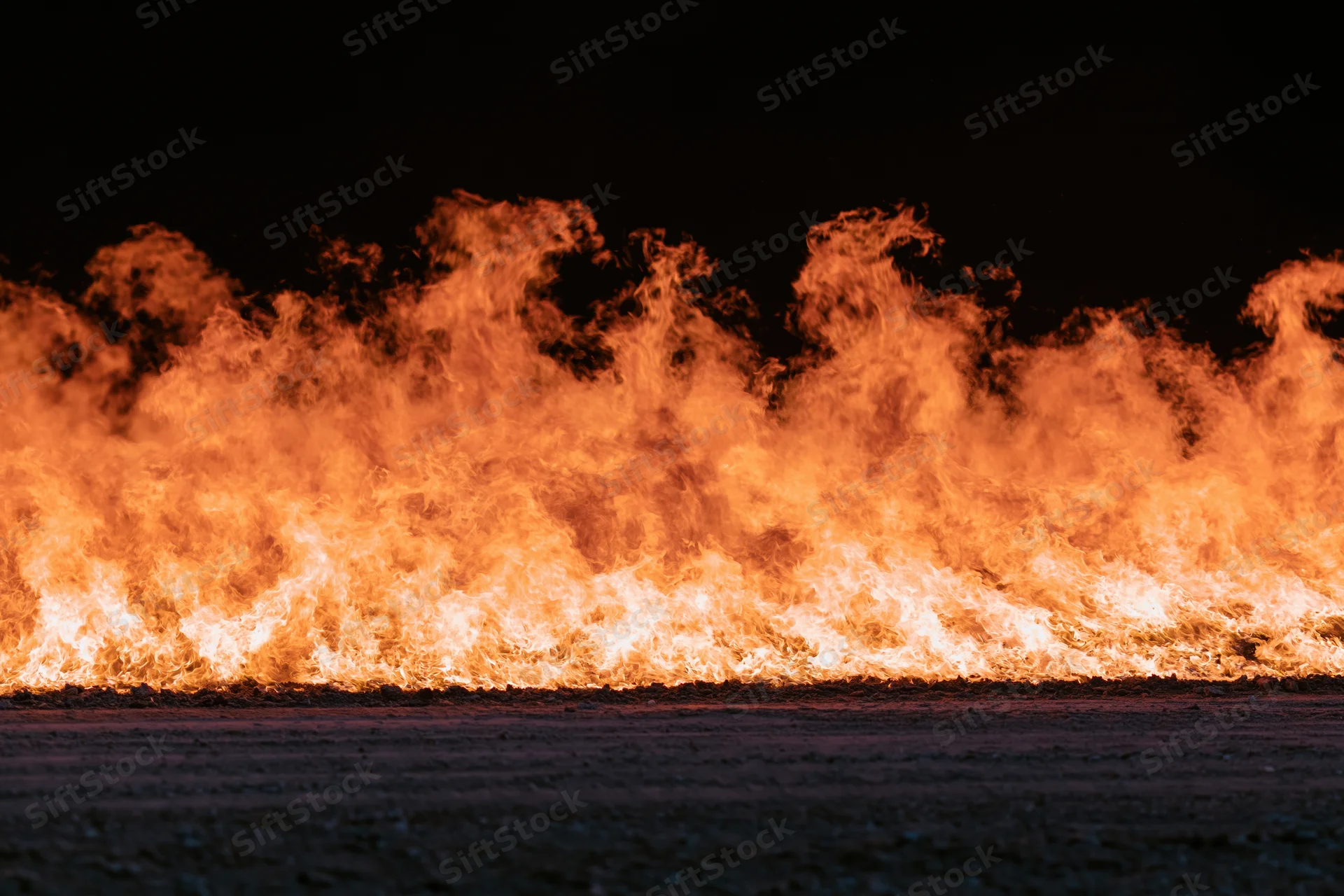Intense industrial fire burning at ground level at night