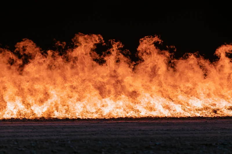 Intense industrial fire burning at ground level at night