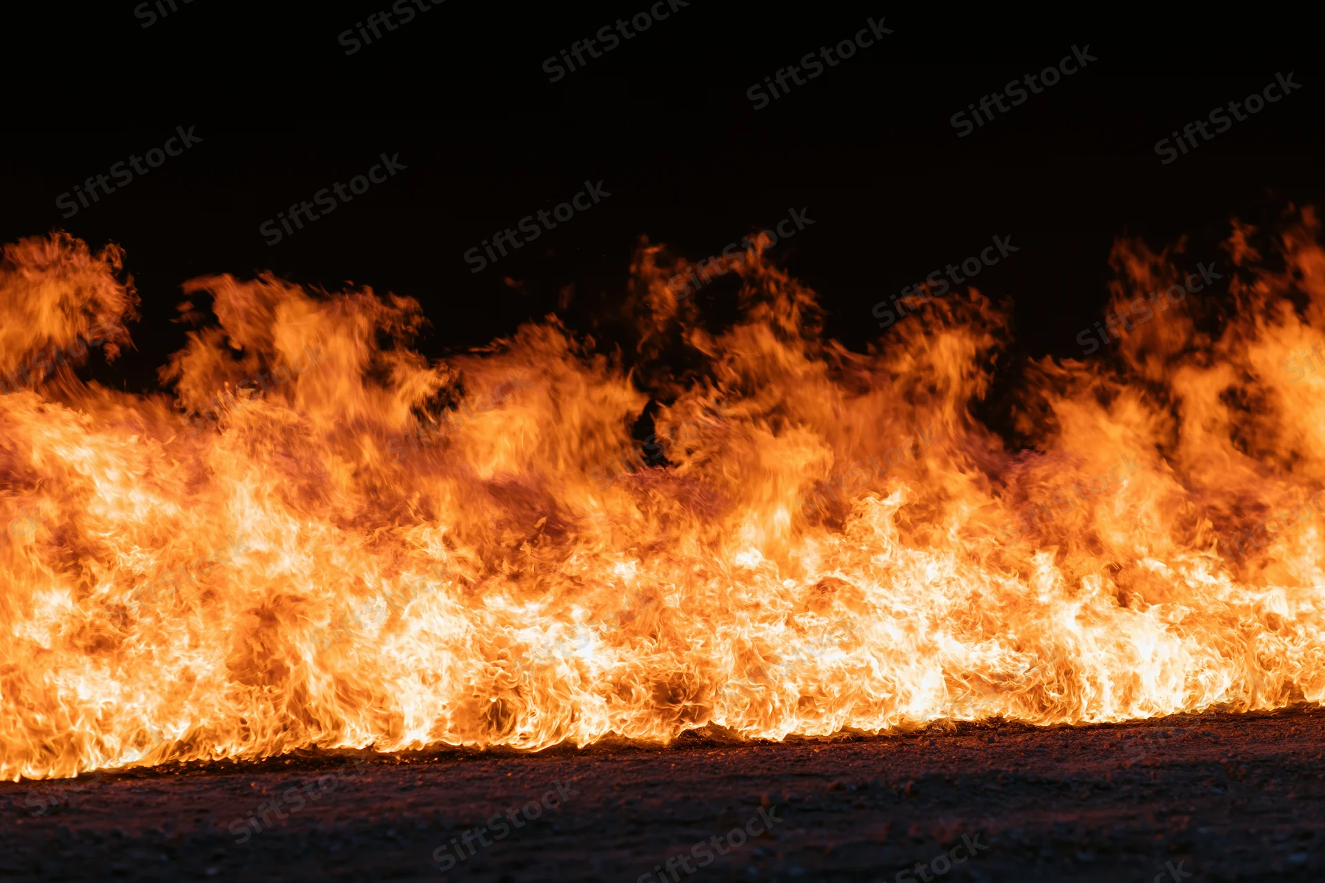 Intense industrial fire burning at ground level at night
