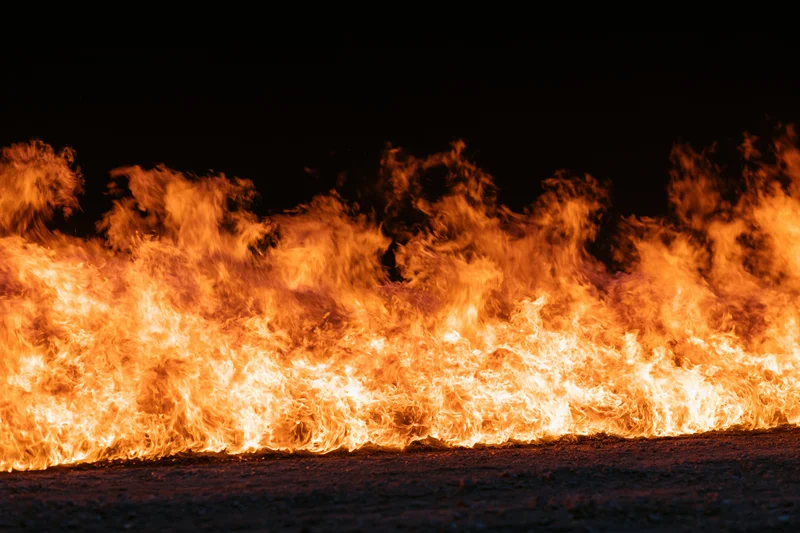 Intense industrial fire burning at ground level at night