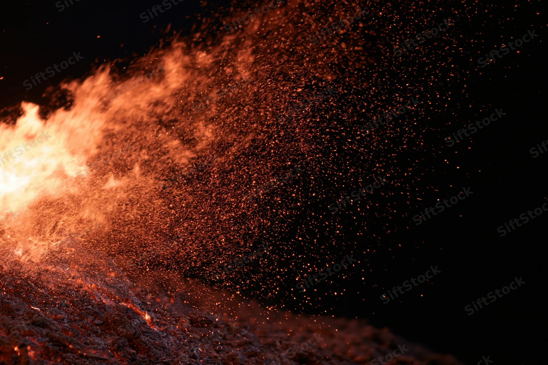 Intense fire burning with flying sparks against a black background