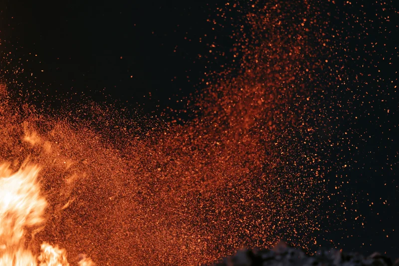 Intense fire burning with flying sparks against black night sky