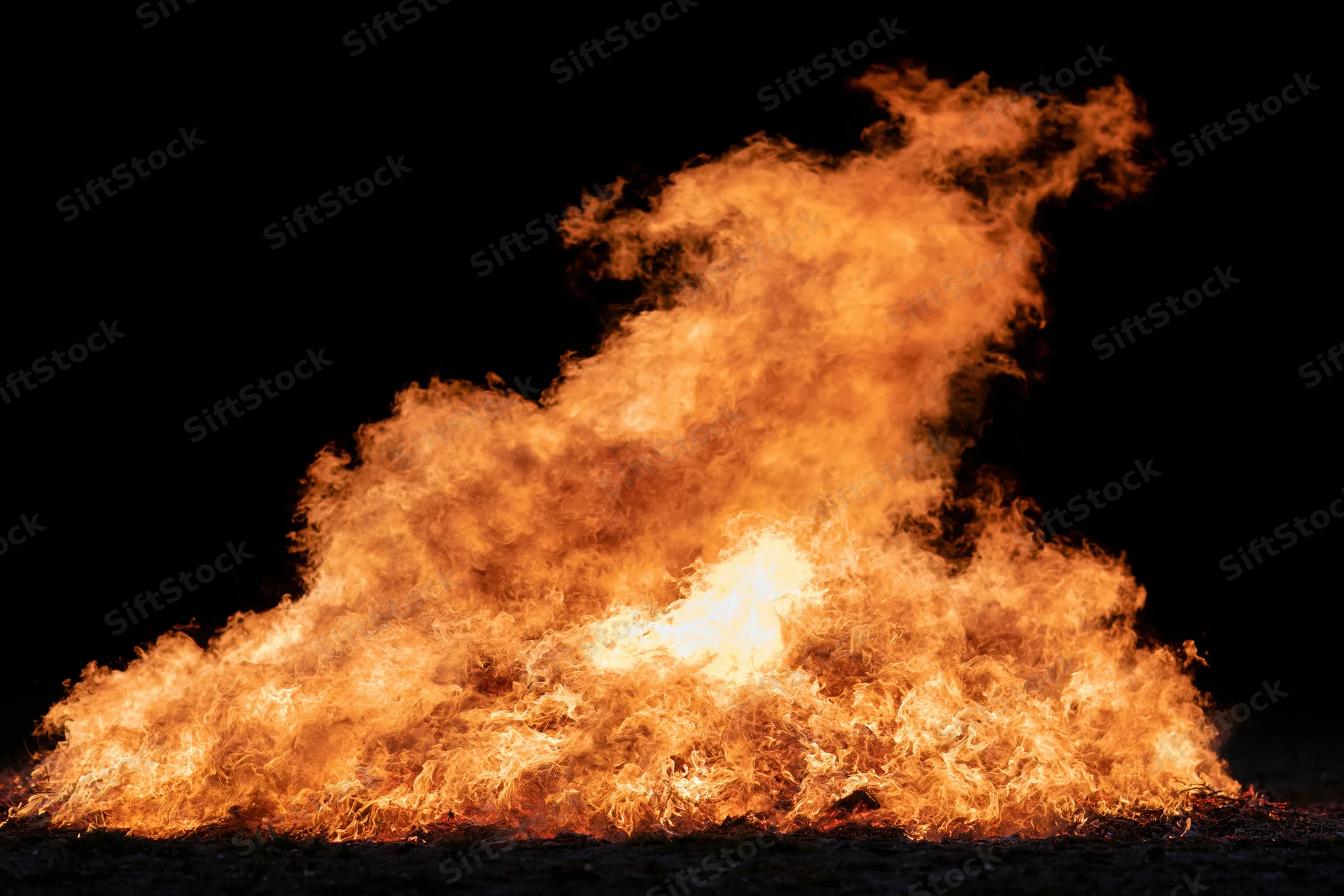 Intense fire burning brightly against a black night background