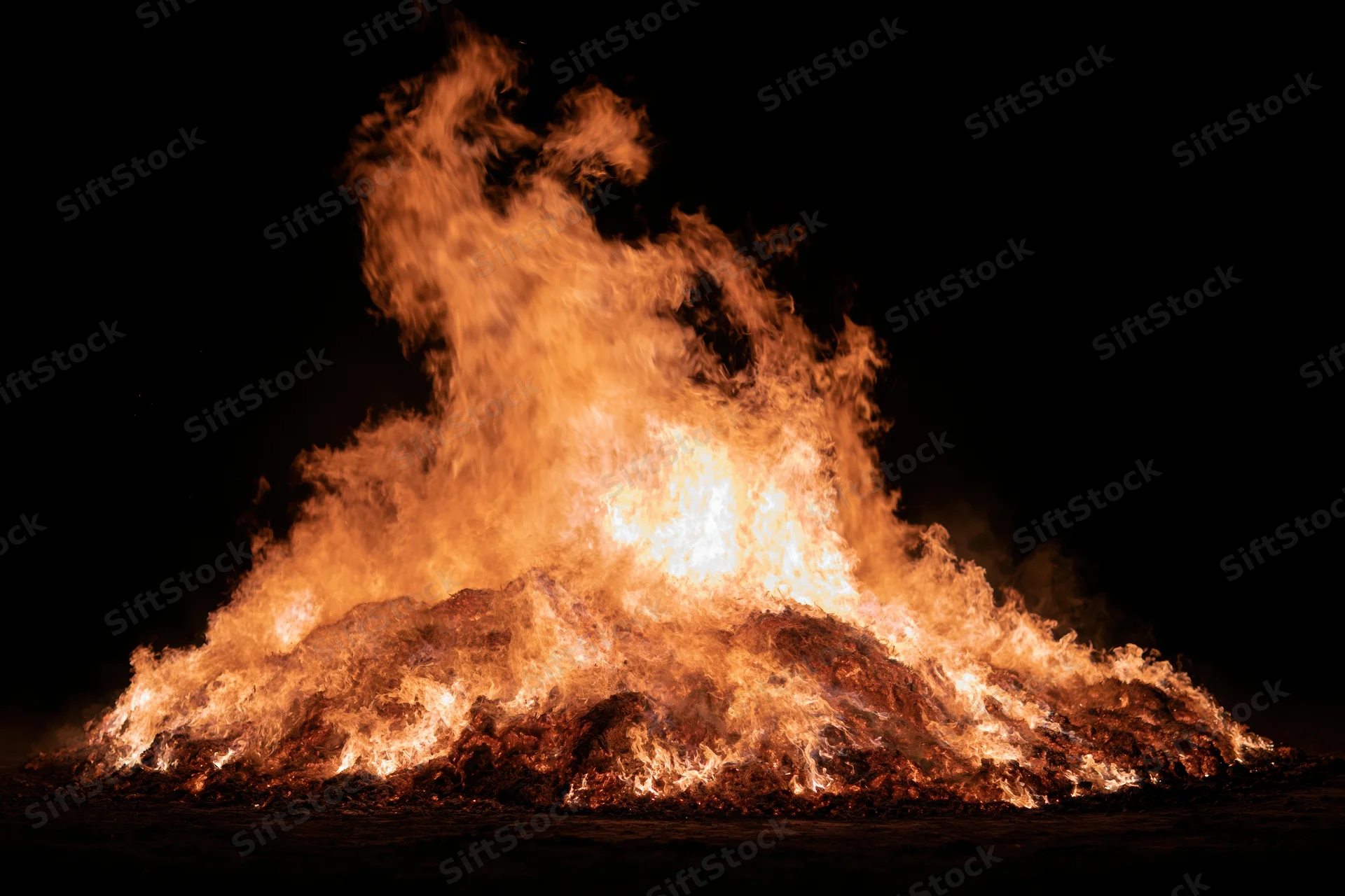 Intense fire burning brightly at night against a black sky
