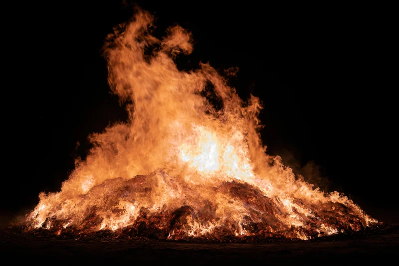 Intense fire burning brightly at night against a black sky