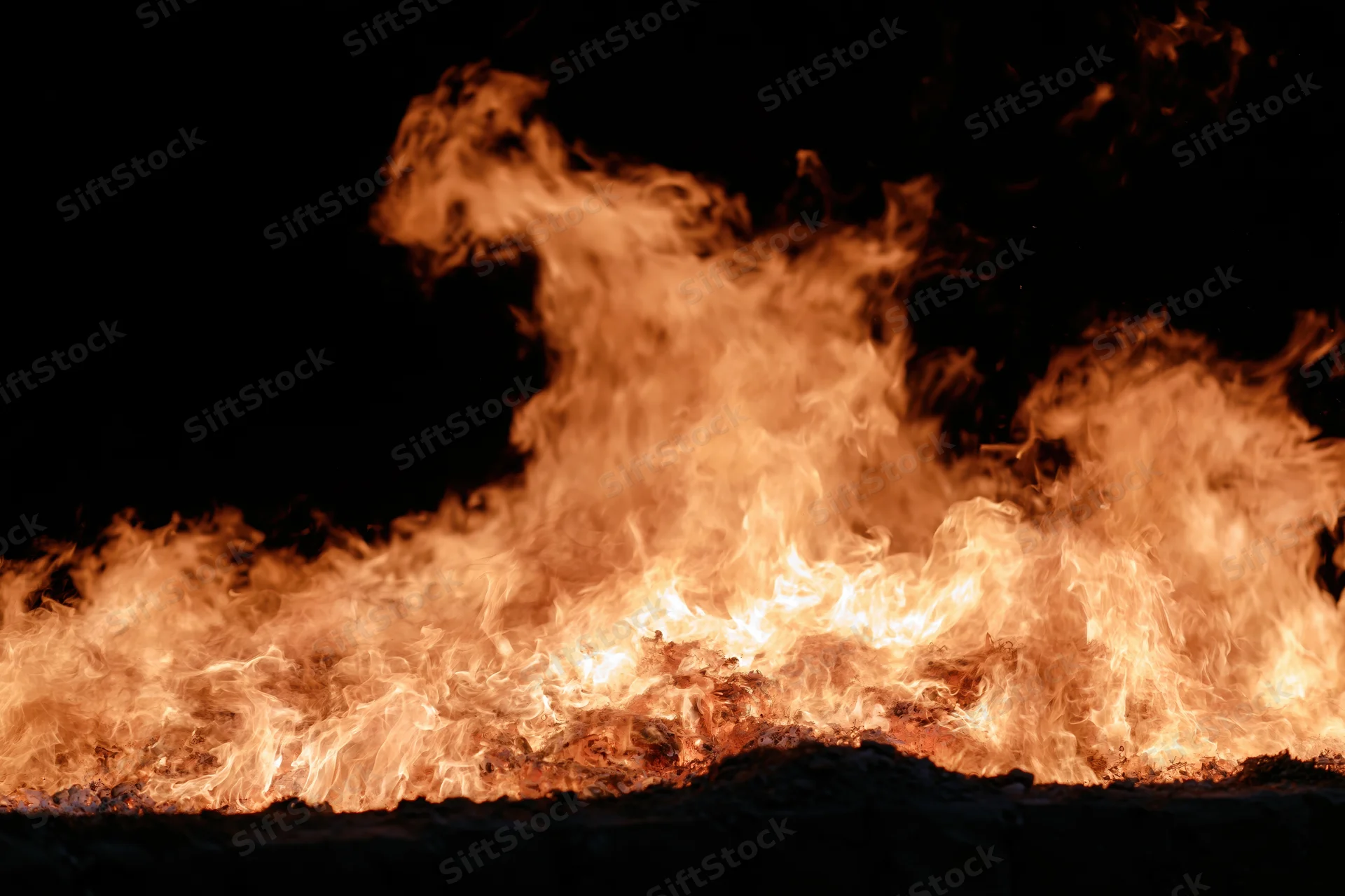 Intense flames burning brightly against a black night background
