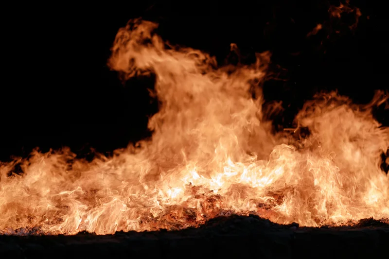 Intense flames burning brightly against a black night background