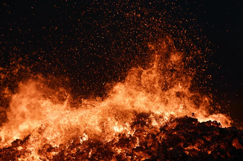 Intense fire burning at night with flying sparks and glowing embers