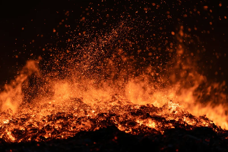 Intense fire burning at night with glowing embers and sparks flying upward