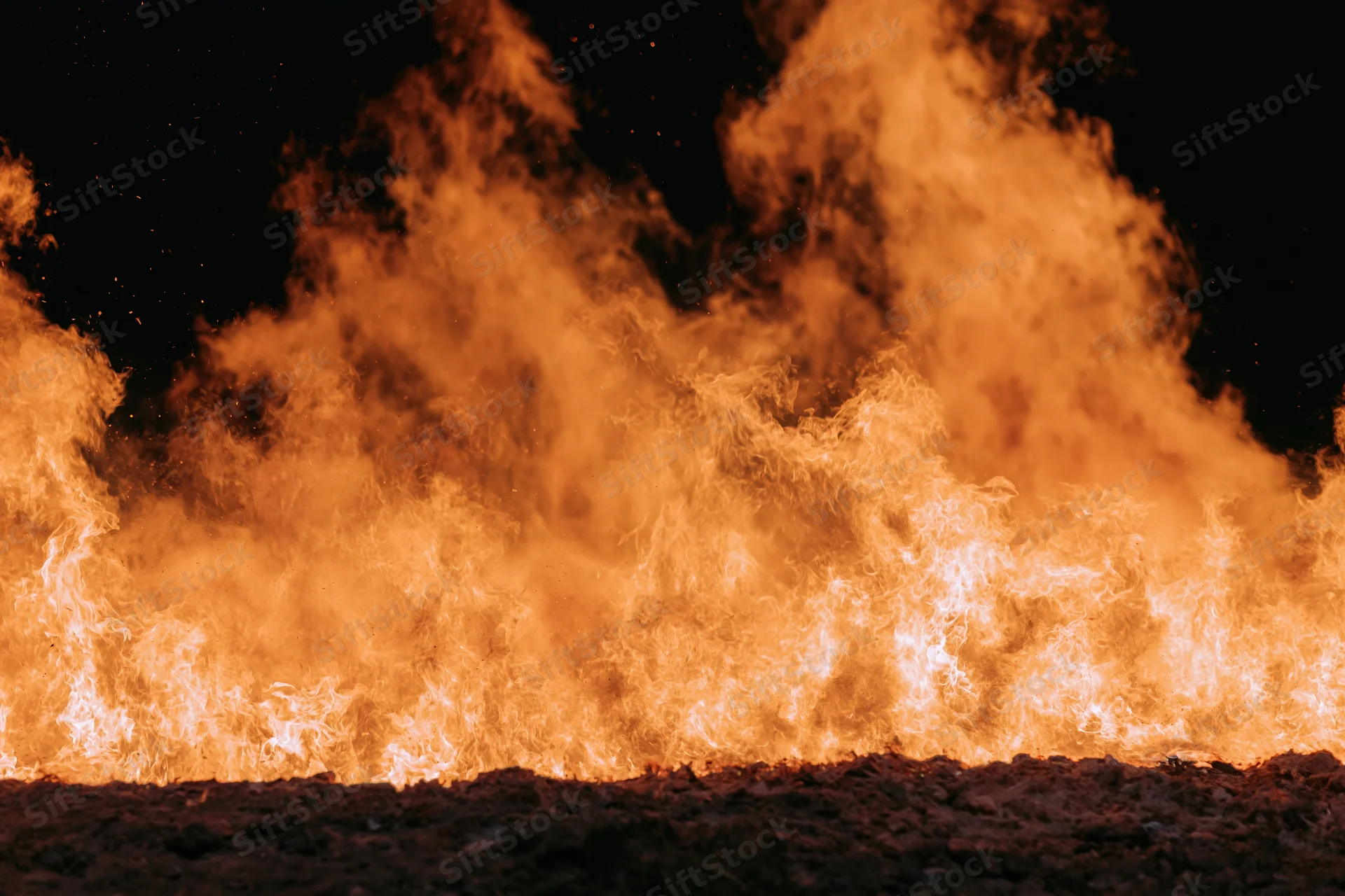 Intense flames rising from ground at night