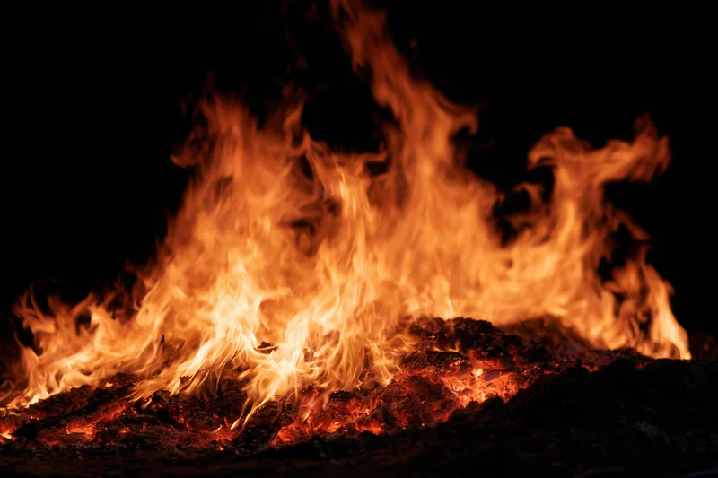 Intense flames burning over glowing embers at night