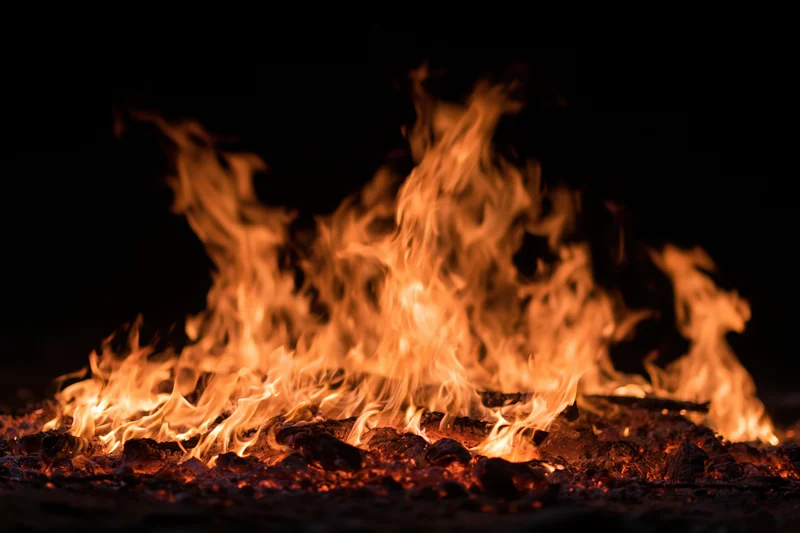 Intense flames burning over glowing embers at night