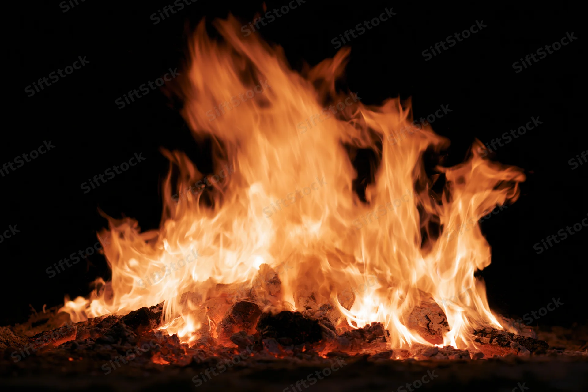 Intense fire burning at night with bright orange flames and glowing embers