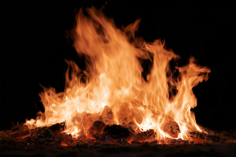 Intense fire burning at night with bright orange flames and glowing embers