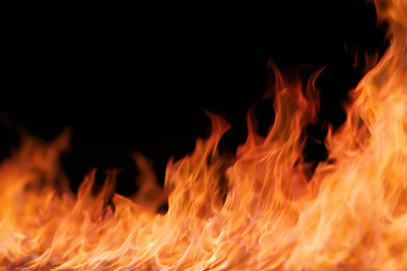 Intense flames burning across the bottom and right side against a black background
